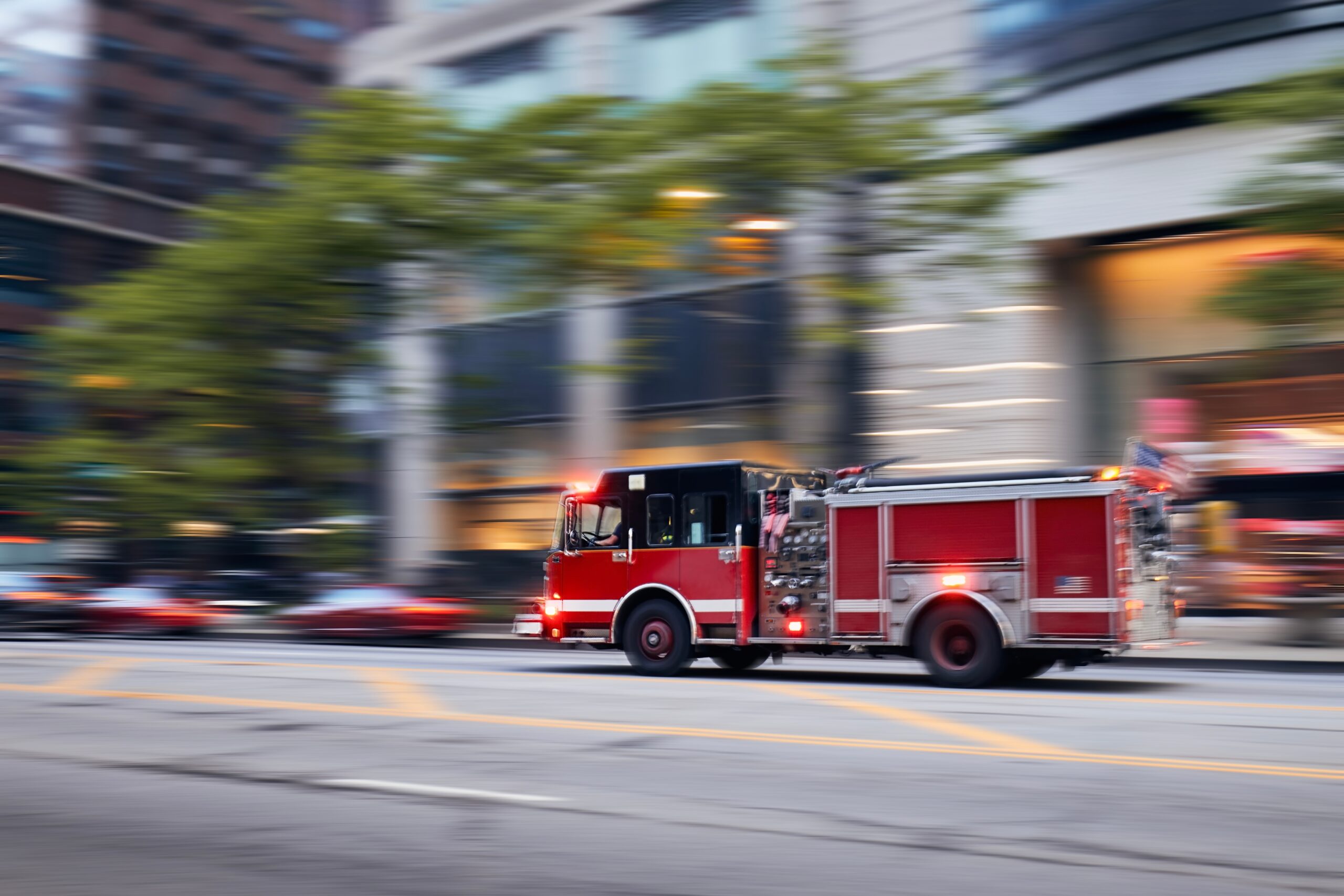 Fast,moving,fire,engine,on,city,street.,firefighters,in,blurred